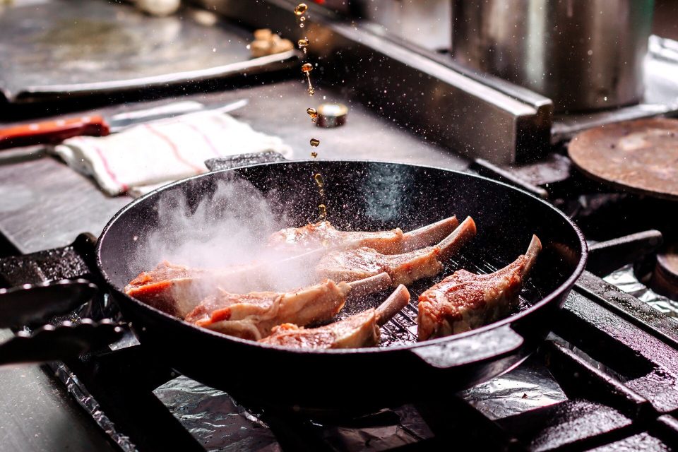Lammkotletter steks i en svart grillpanna av gjutjärn på en gasspis
