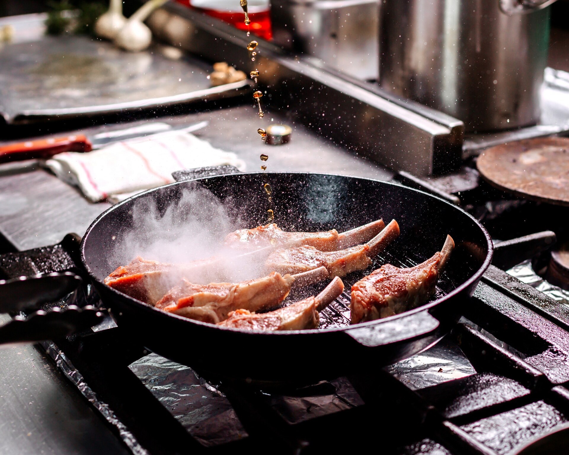 Lammkotletter steks i en svart grillpanna av gjutjärn på en gasspis